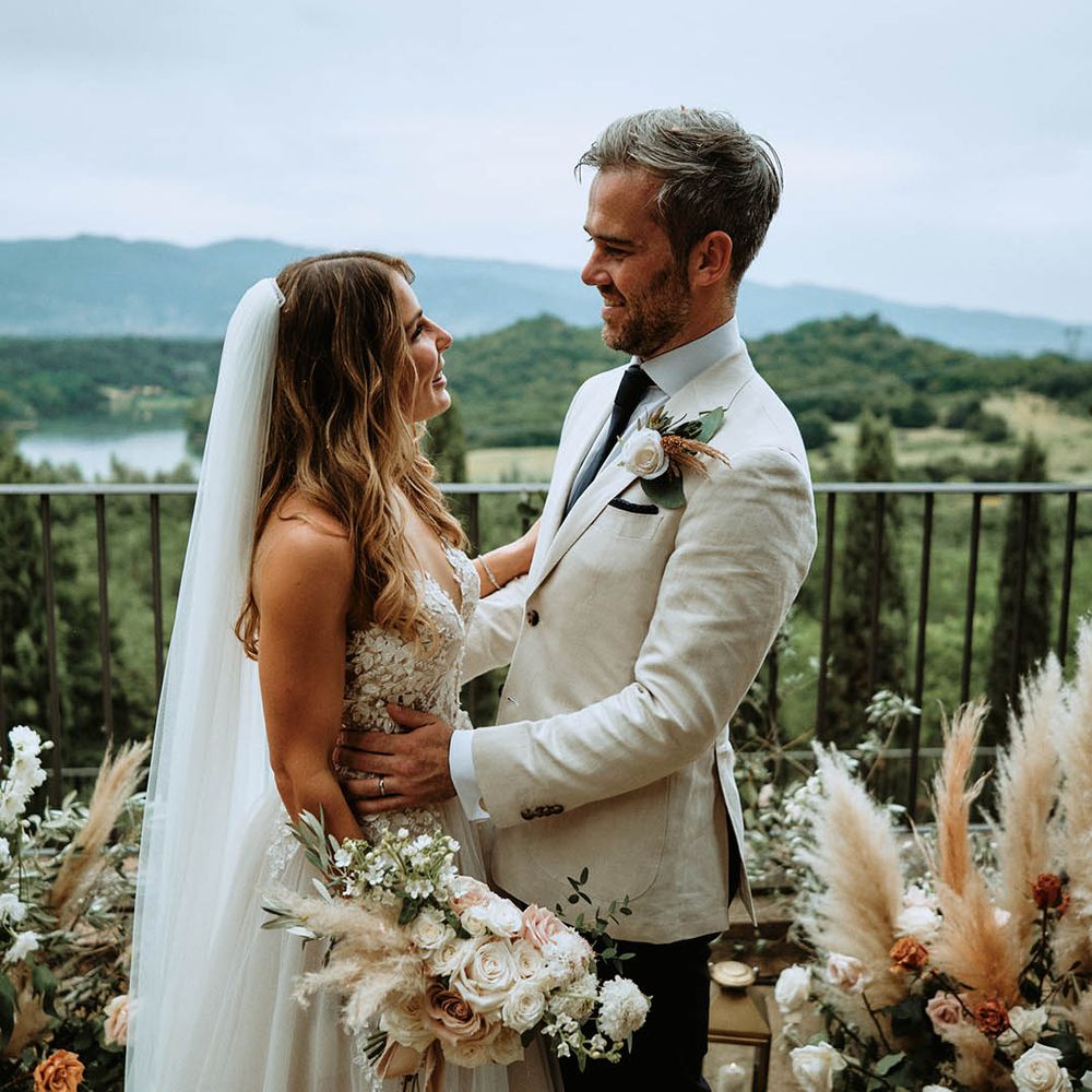 Bride and groom embrace at altar surronded by pampas grass decor and lanterns at destination wedding in Italy