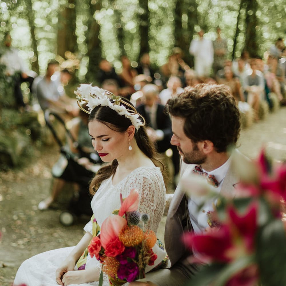 Bride in boho bridal crown and groom in griege suit sitting down during their wedding ceremony in Italy 