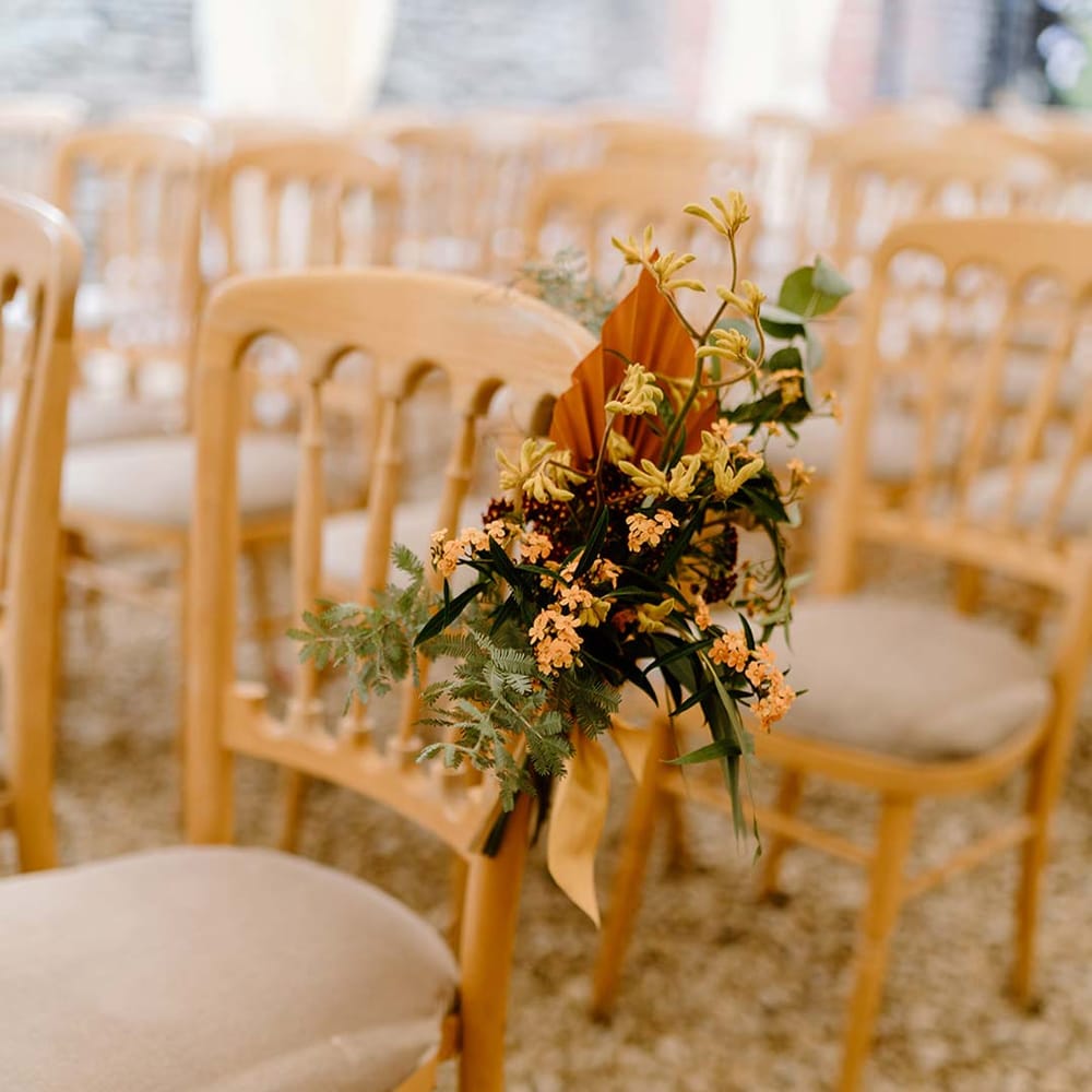Wedding aisle flower inspiration at Broadfield Court - floral arrangement with yellow tall kangaroo paws, orange osmanthus flowers, foliage and dried flowers 