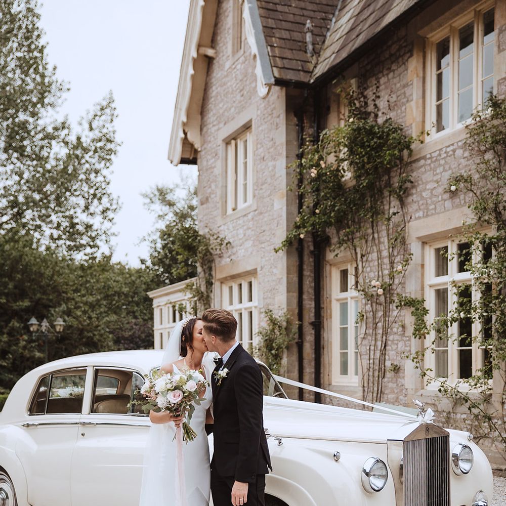 Rolls Royce cream wedding car with the bride in a satin wedding gown with the groom in black tie 
