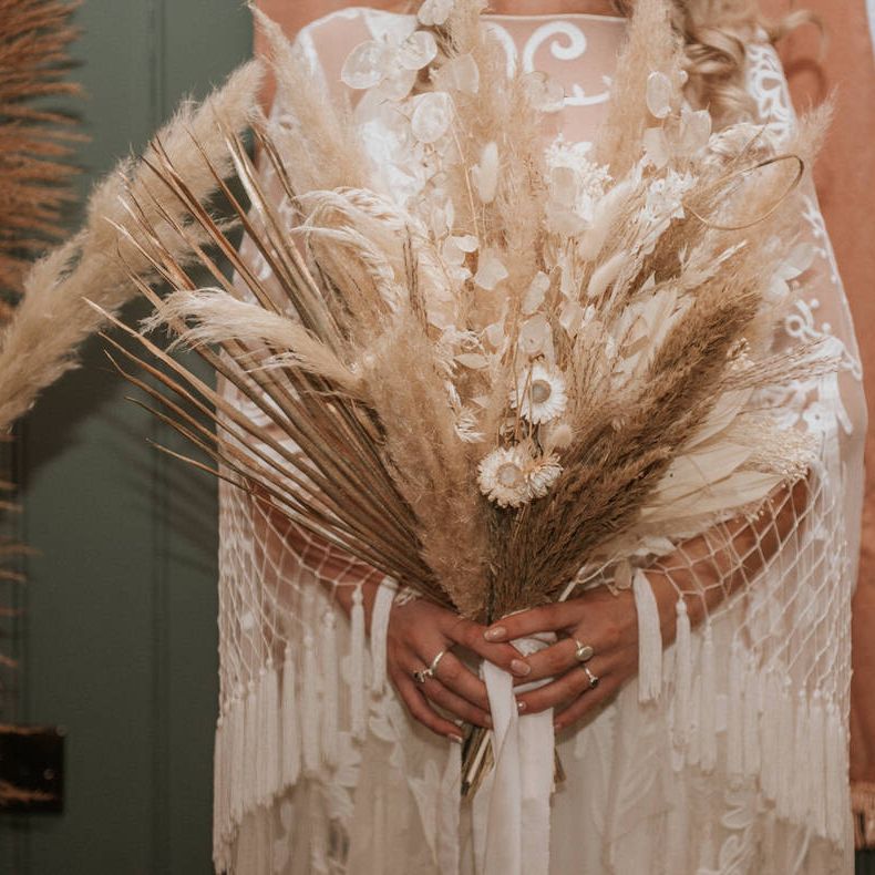 Bride holds dried flowers and pampas grass bouquet at wedding reception