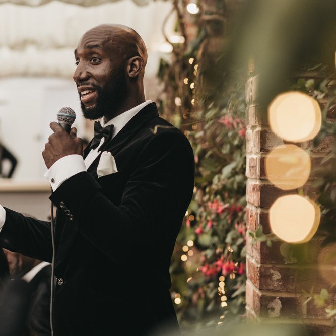 Black groom in a velvet tuxedo and bow tie giving his wedding speech at the Northbrook Park reception 