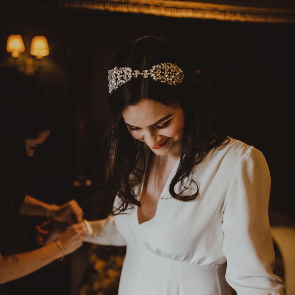 Bride wearing jeweled hair accessory and long sleeved wedding gown