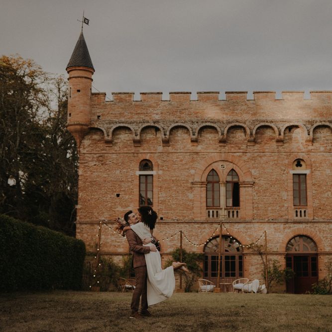 Groom picking up his bride with Château de Caumont in the background 