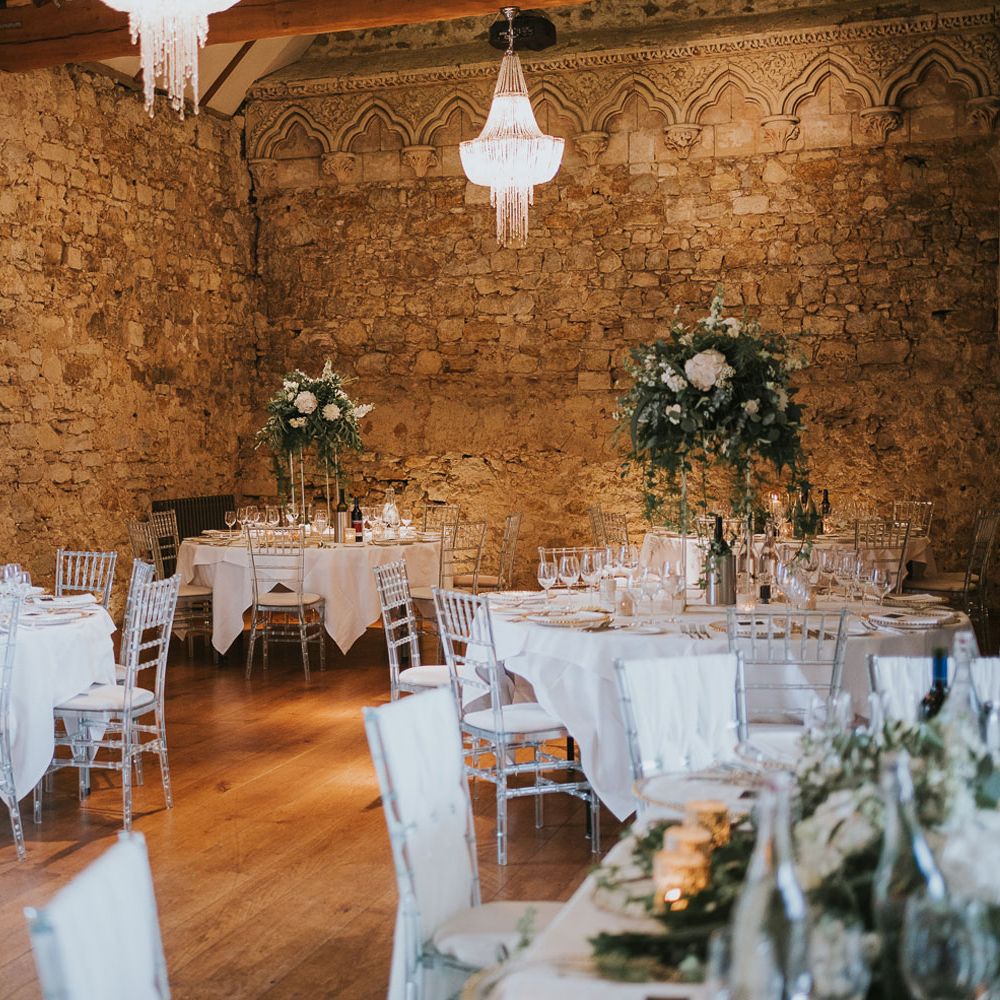 Elegant round white wedding tables with perspex bamboo chairs and white and green floral centrepieces for Notley Abbey wedding reception