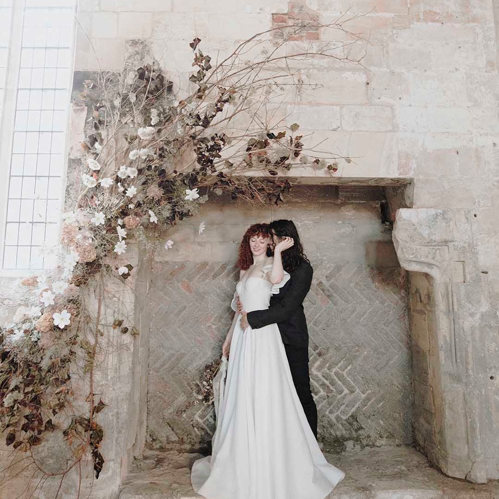 Bride and groom portrait in the giant fireplace at medieval wedding venue, Blackfriars Priory in Gloucestershire 