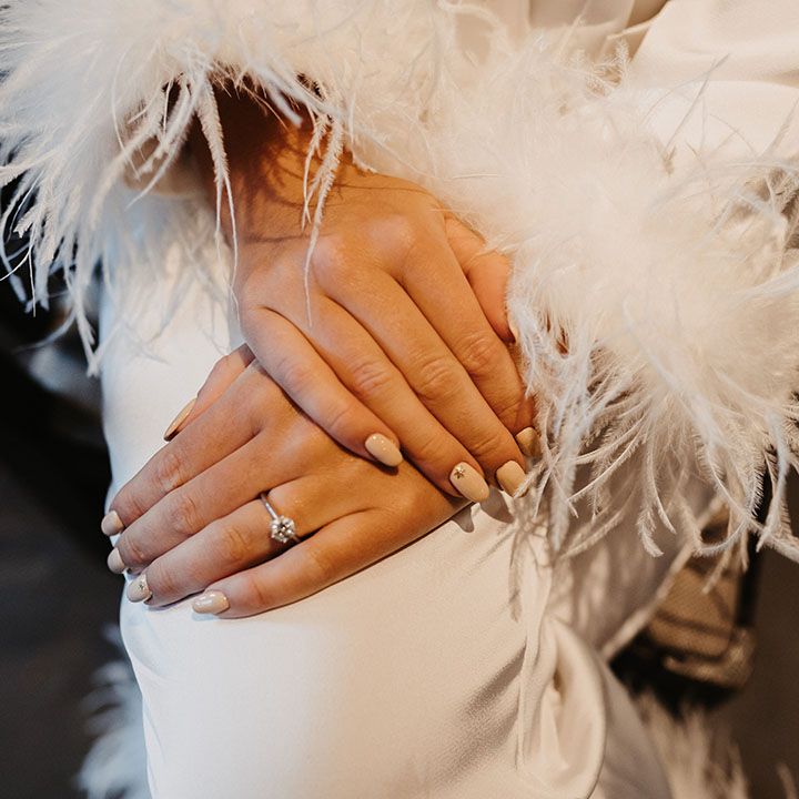 Nude and neutral nails with gold stars on accent nail with round diamond engagement ring and ostrich feather robe