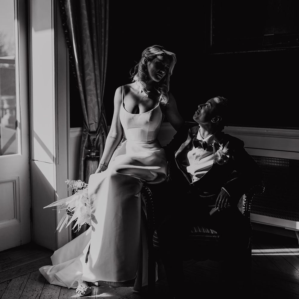 Black and white portrait of a bride sitting on her partners lap in a tuxedo at Hodsock Priory wedding venue 