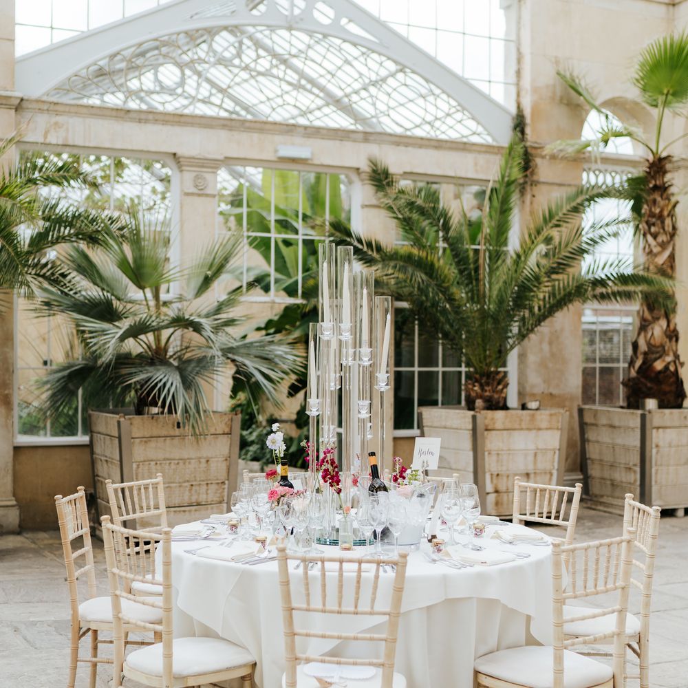 Clean tablesape complete with bright florals and pillar candles in glass cases 