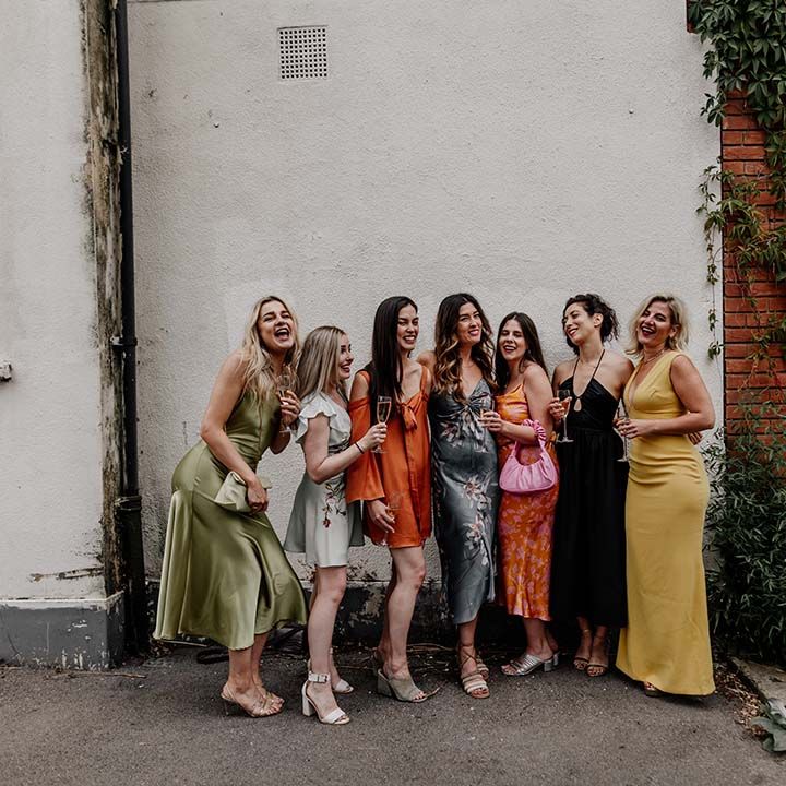 Bridal party in mismatching bridesmaid dresses posing and smiling at Hackney Studios