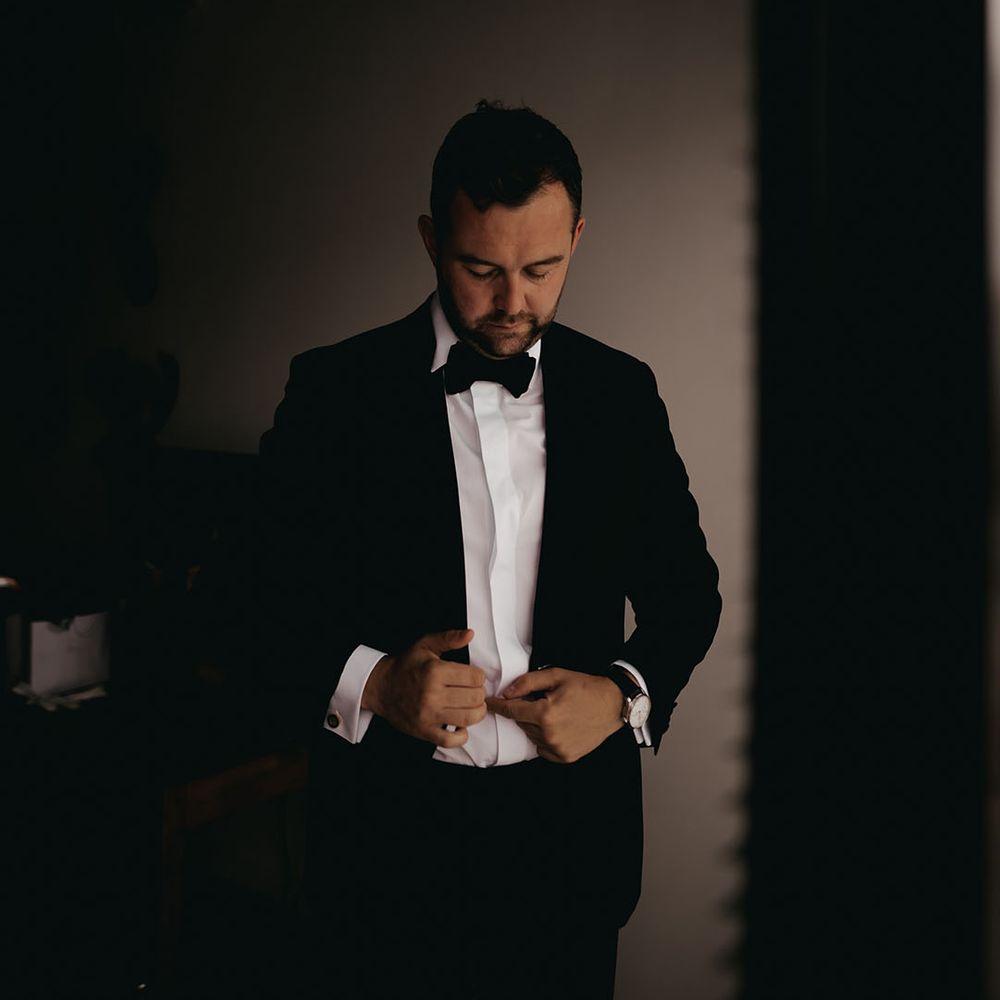 Getting ready preparation as the groom gets into his traditional and classic black tie 
