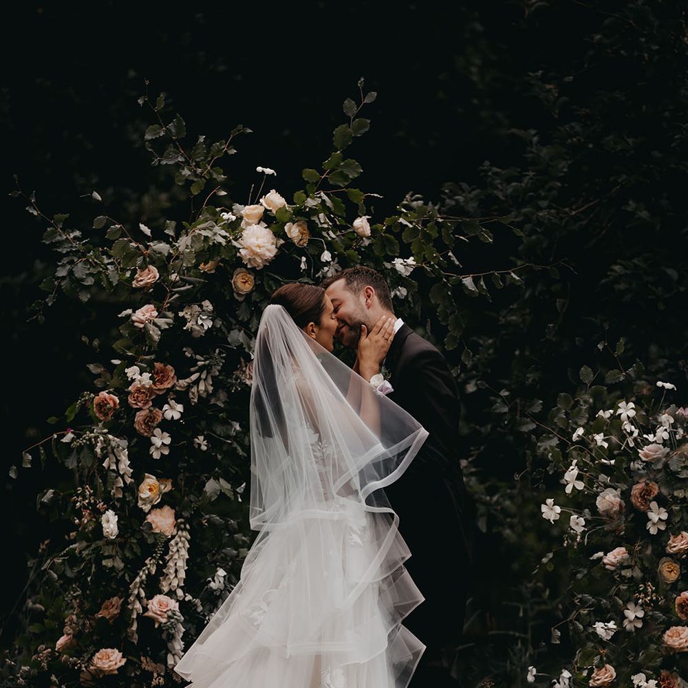 Bride and groom share their first kiss for their outdoor ceremony at Anran with flower column altar decor 