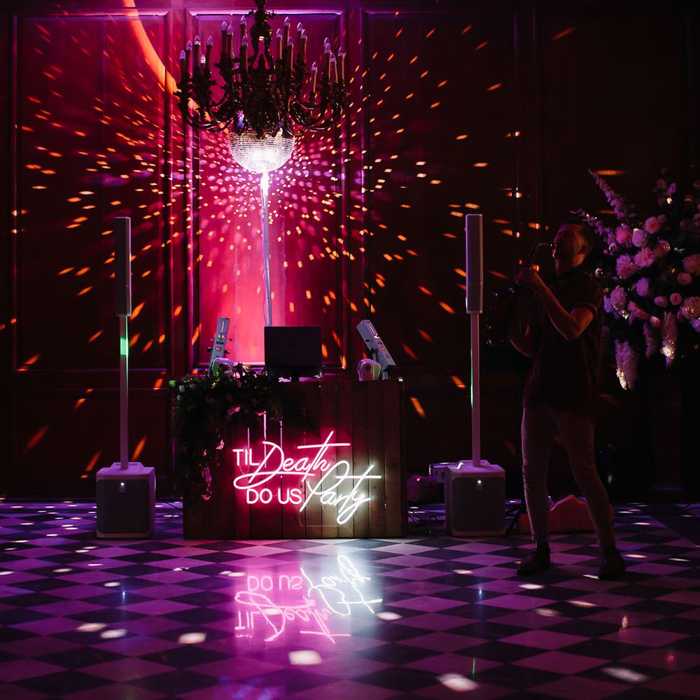 DJ booth with laser lights and bright neon wedding sign
