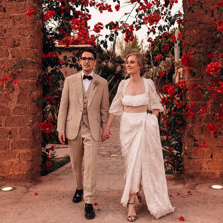 Bride in lace long sleeve crop top and maxi skirt with the groom in three piece cream suit 