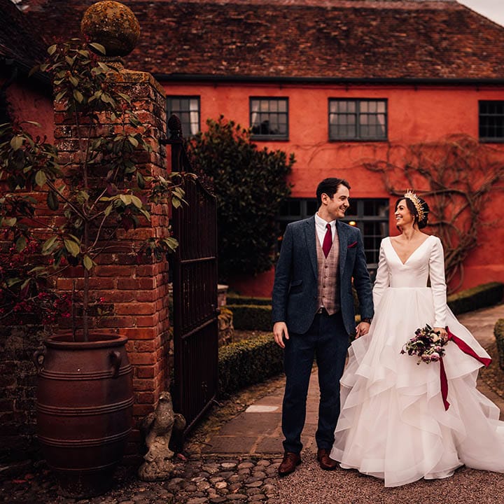Groom in three piece blue suit with the bride in a long sleeve traditional wedding dress with ruffle wedding skirt 