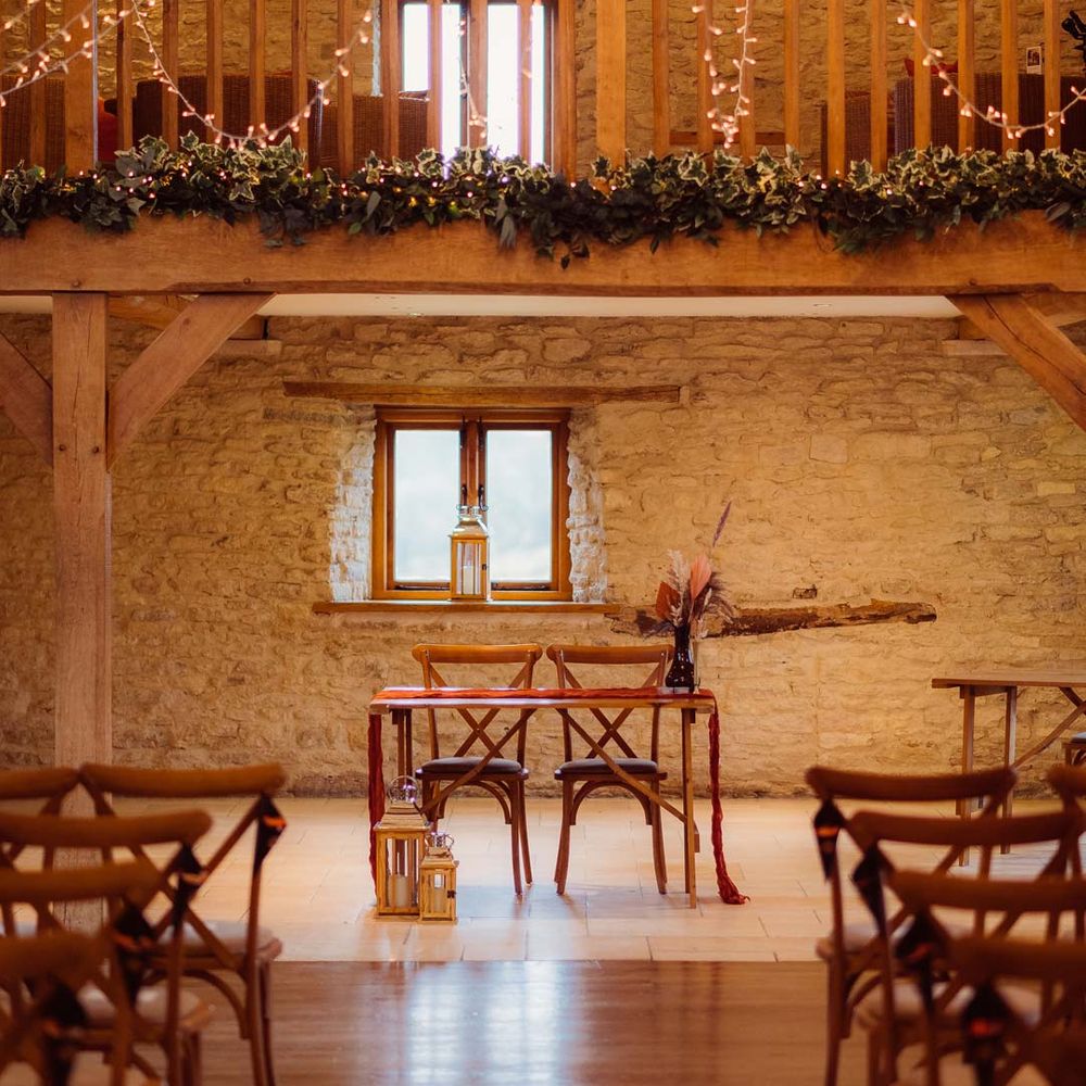 Kingscote Barn Tetbury wedding venue reception room with fairy lights, festoon lighting and exposed brick