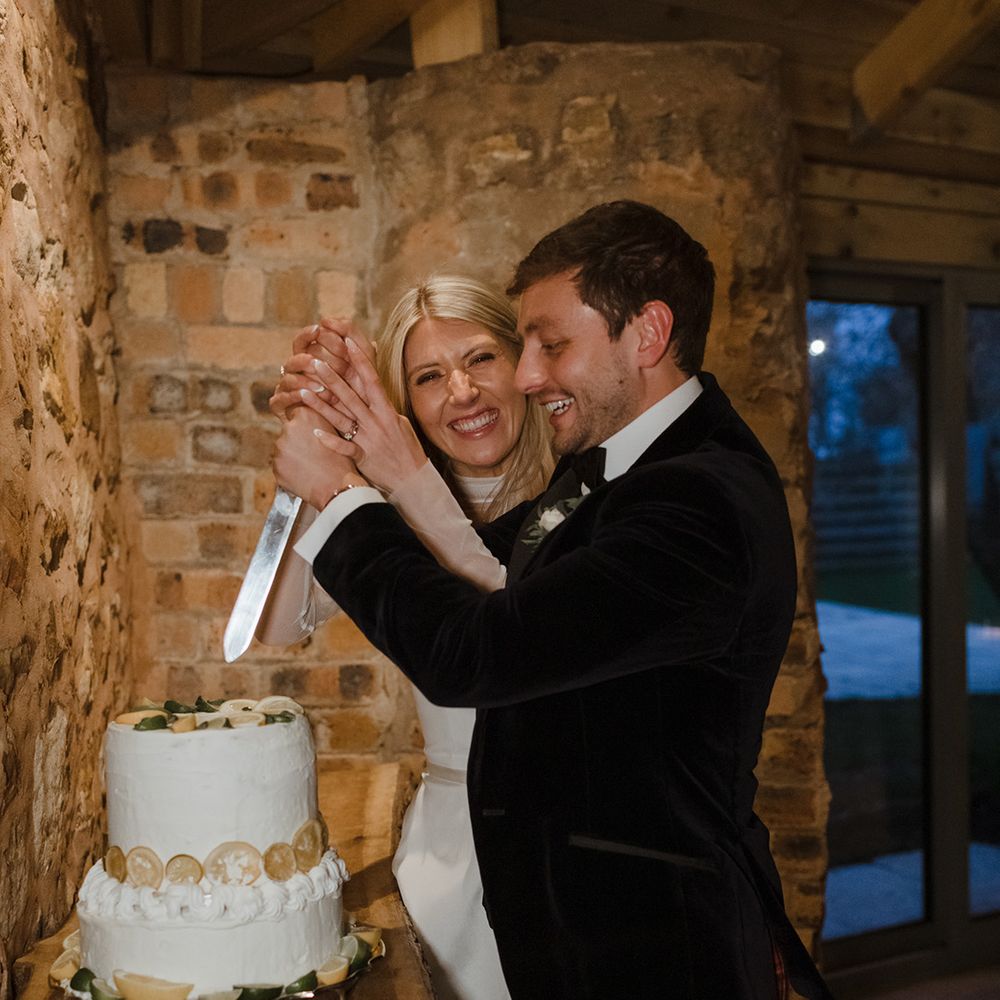 Bride and groom cut their two tier white iced wedding cake with lemon slices 