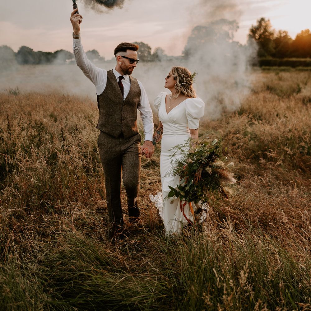 Grey smoke flare being waved by groom for fun wedding couple portrait 