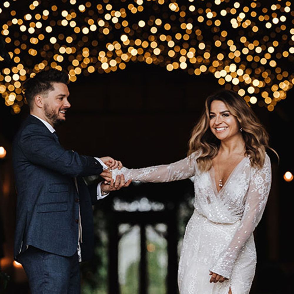 Bride in sparkly wedding dress dancing with groom under magical fairy lights at one of the best winter wedding venues 