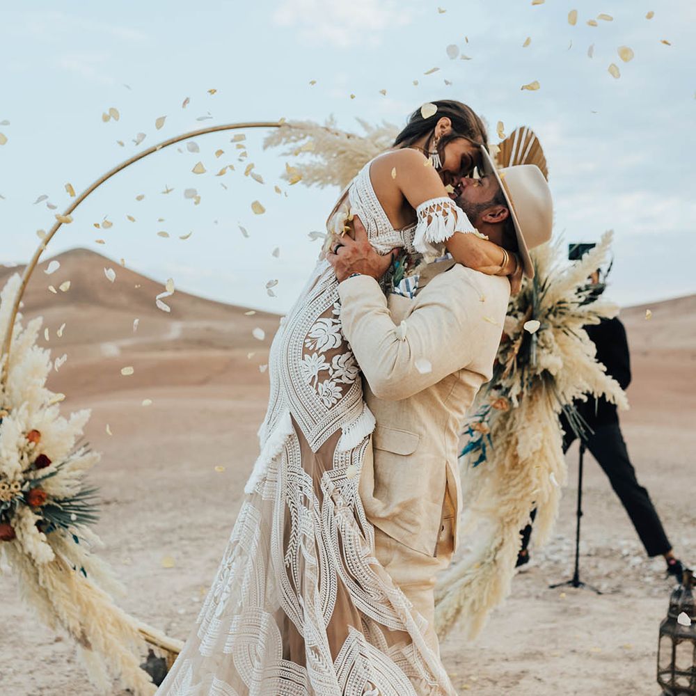Romantic confetti wedding photo with bride leaping into the groom's arms for a kiss 