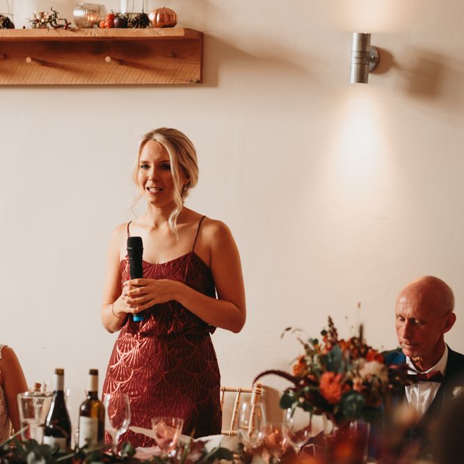 Bridesmaid in rust coloured dress delivering a speech
