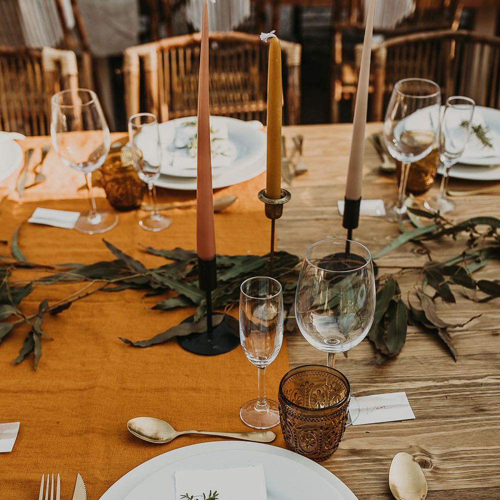Place setting with coloured taper candles and olive branches 