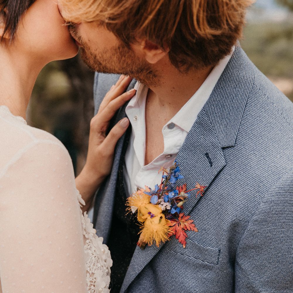 Groom wears colourful floral buttonhole