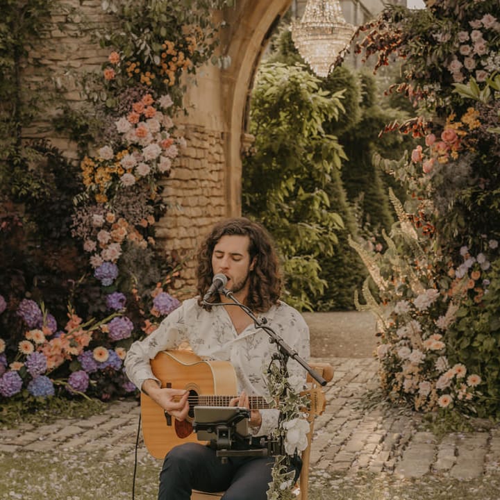 Musician singing and playing guitar in front of the castle arch at Euridge Manor 