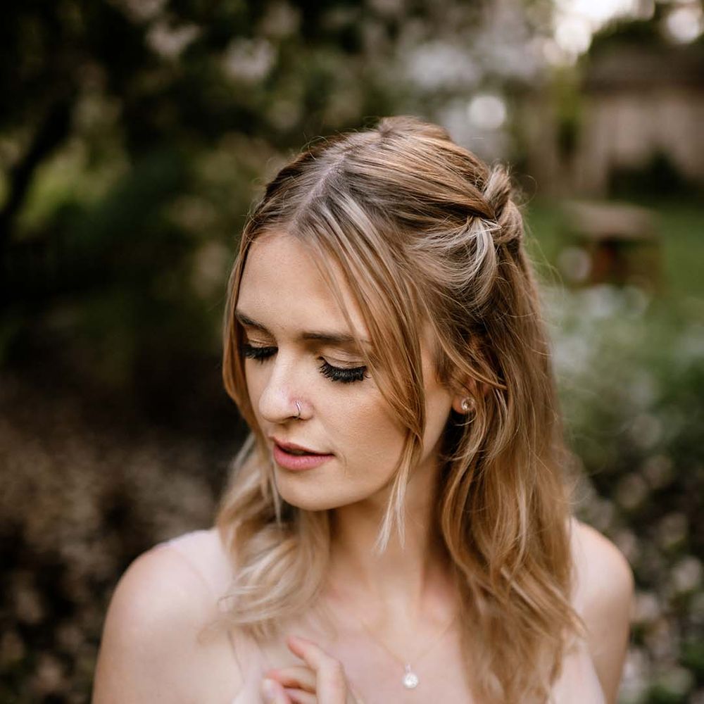 Bride in a blush pink wedding dress with a half up half down wedding hairstyle 
