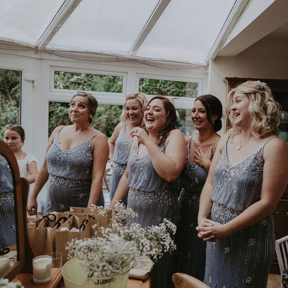 Bridesmaids in blue beaded cami bridesmaids dresses standing in conservatory before Isle of Wight wedding with macrame wedding decor