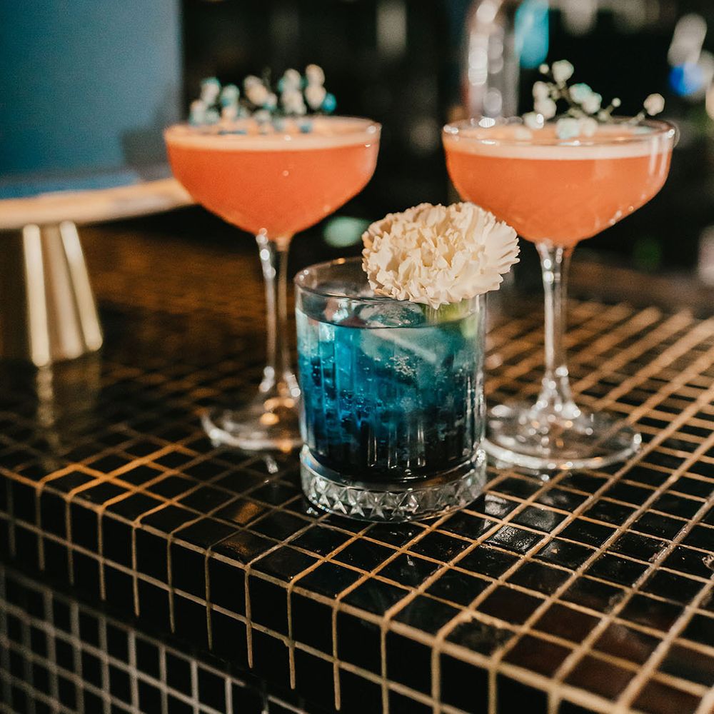 Pink and blue cocktails on the bar at a stylish teal wedding reception 