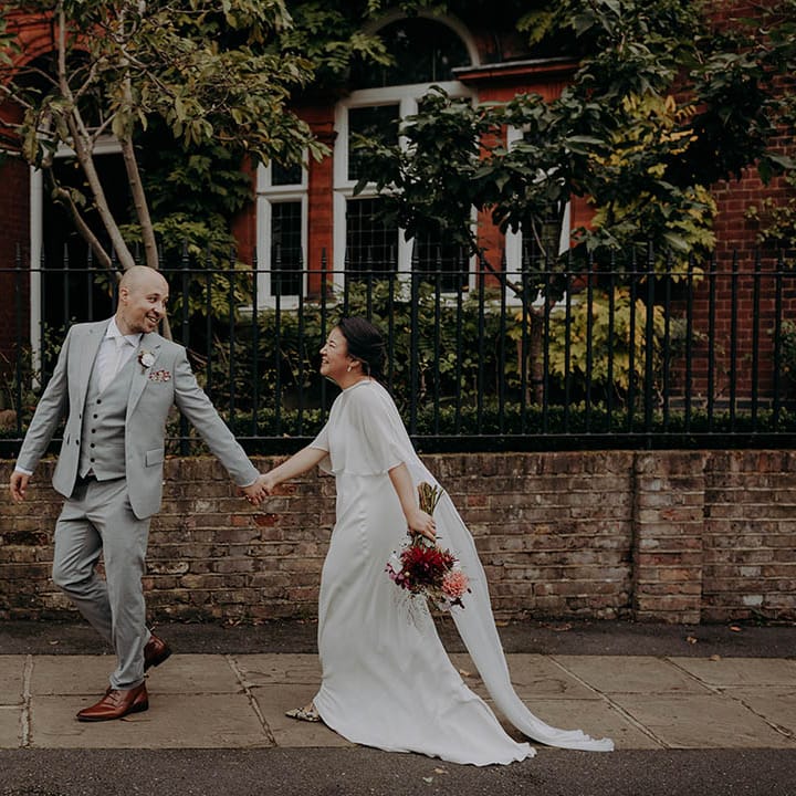 Groom leads his bride as they walk through streets on their wedding day