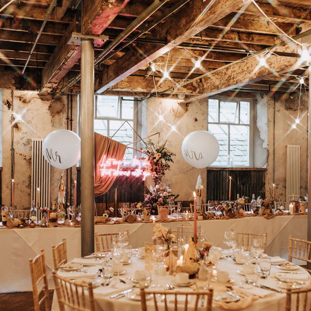 Wedding reception room at Holmes Mill with white round wedding tables, wooden chairs and elegant wedding styling with candles and fairy lights