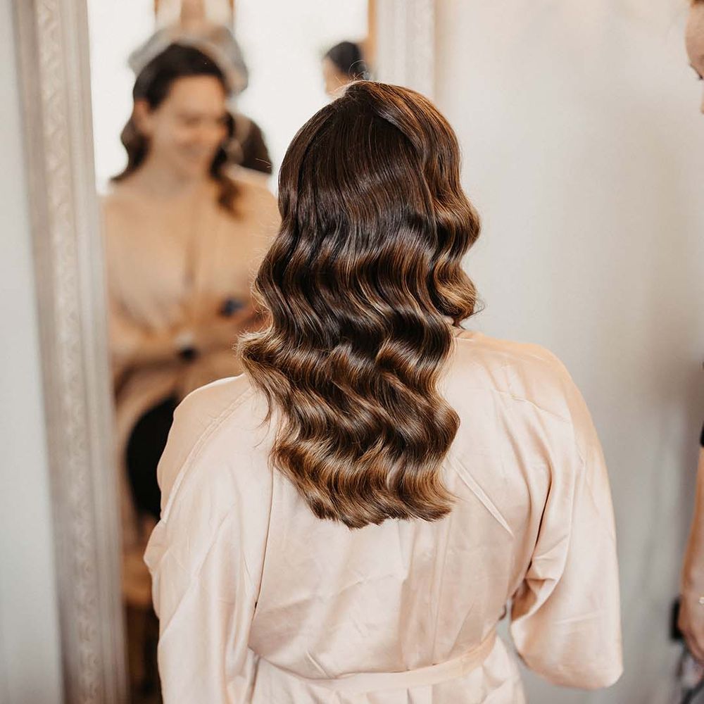 Bridesmaid in pale pink satin dressing gown with Hollywood style curled hair