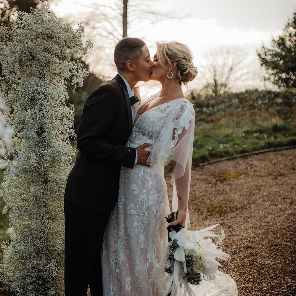 LGBTQI+ couple kissing at their Hodsock Priory winter wedding in black tie suit and lace wedding dress