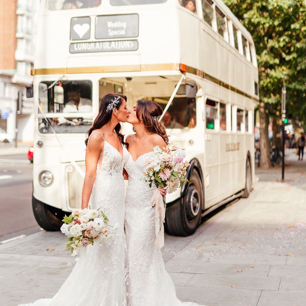 London Lesbian wedding with two brides kissing in front of a cream double decker bus
