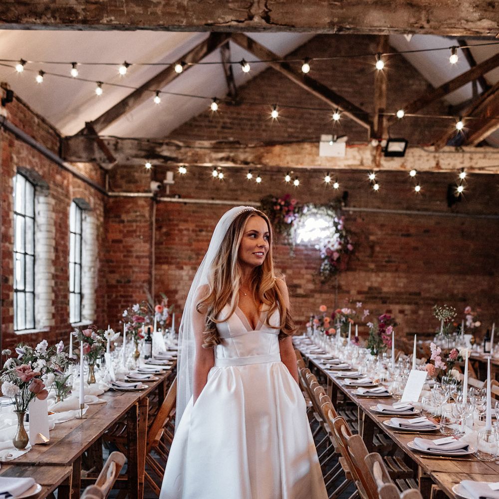Bride in a princess wedding dress with V front and full skirt standing in her wedding reception at The Loft Studios 