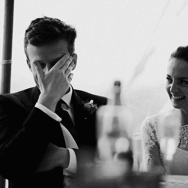 Bride laughs and groom looks embarrassed during wedding speeches at the reception of traditional and classic wedding 