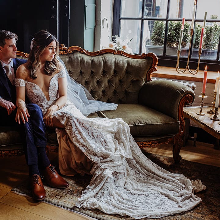 Bride and groom sit relaxed together on a sofa 