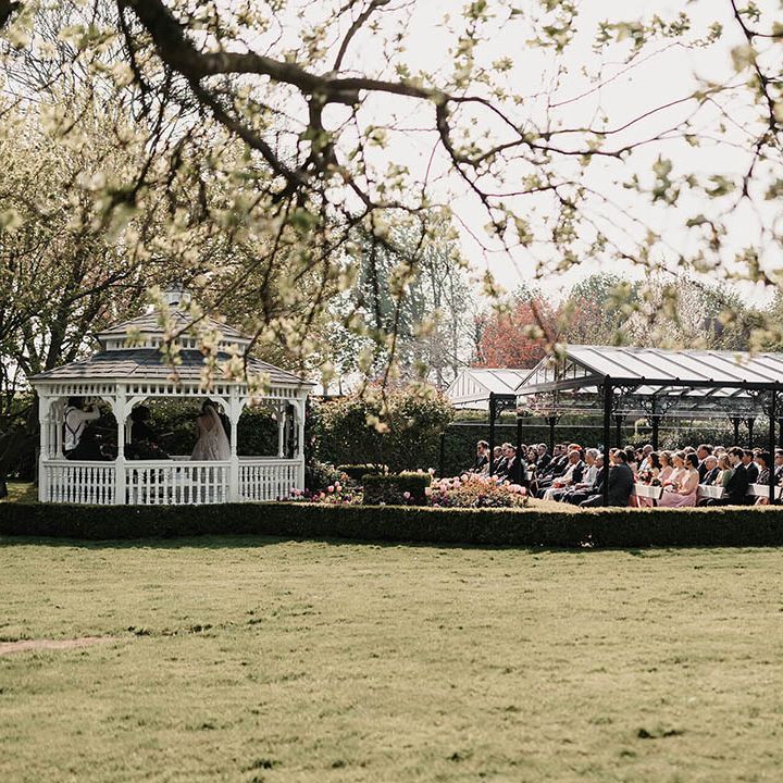 Wedding guests sit outside under cover for the outdoor wedding ceremony 