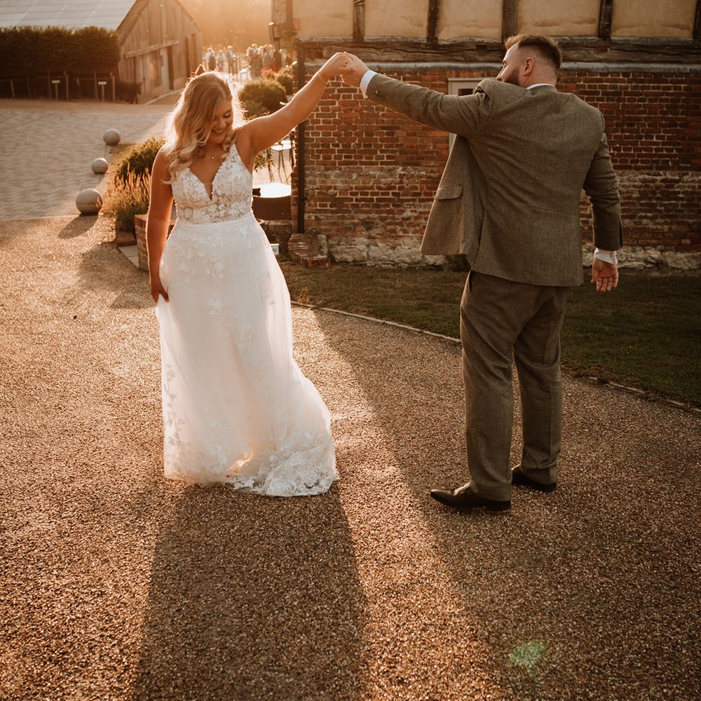The groom spins the bride around during the sunset 