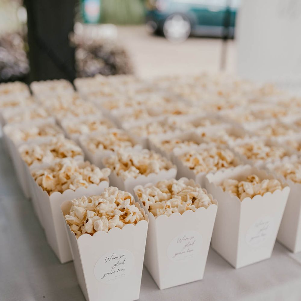 Scalloped edge boxes of popcorn for the wedding guests with personalised stickers 