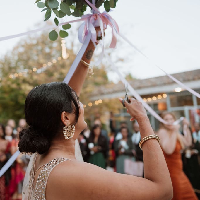 Bride cutting the ribbon attached to the wedding bouquet 