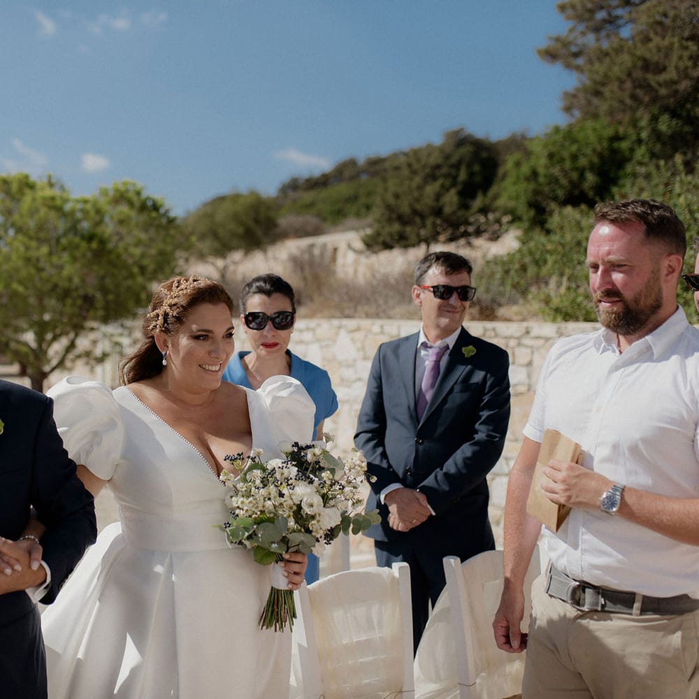 Bride in puff sleeve satin white wedding dress walks into wedding ceremony with father of the bride