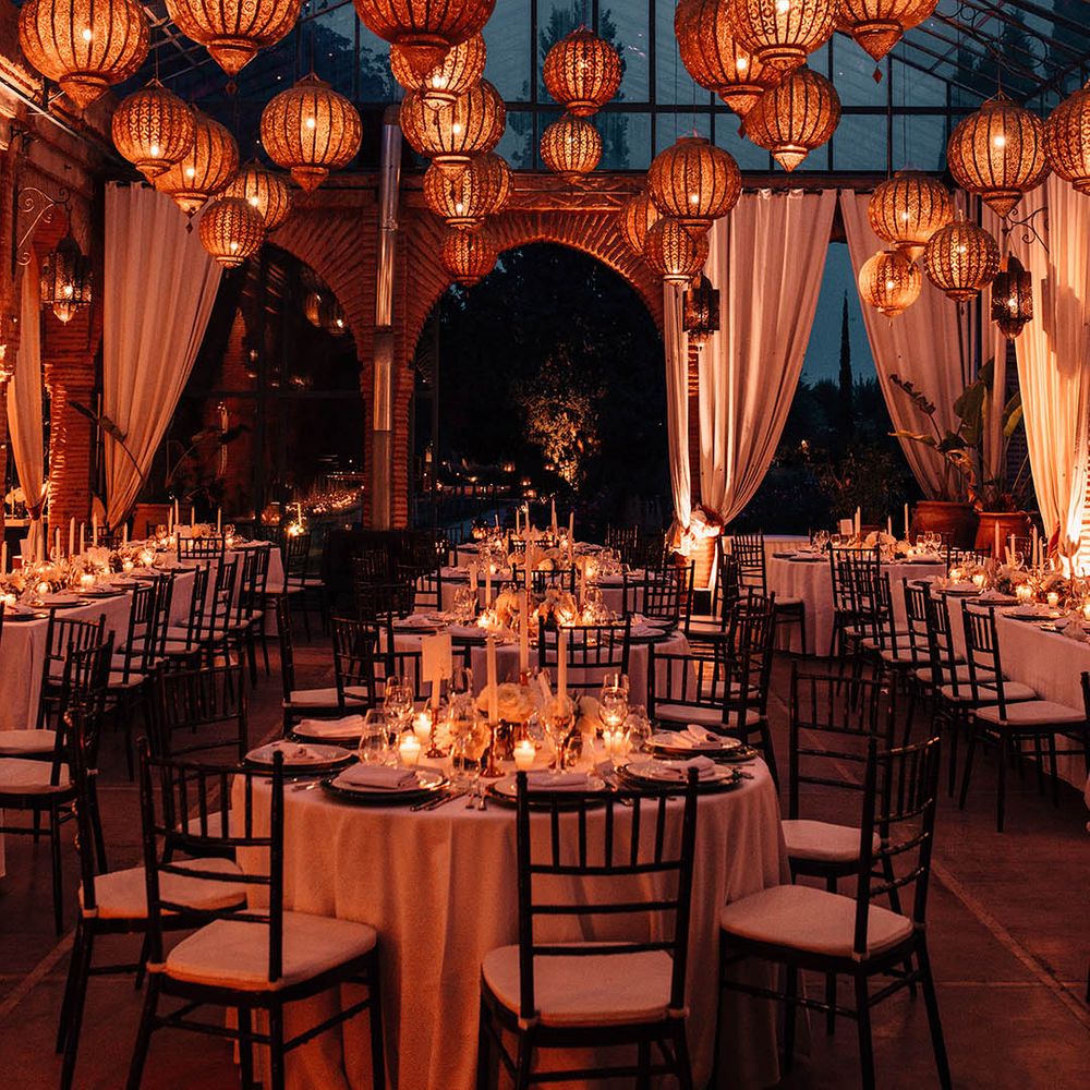 Beldi Country Club glass house wedding venue with golden lanterns and candlelight with white wedding drapery 