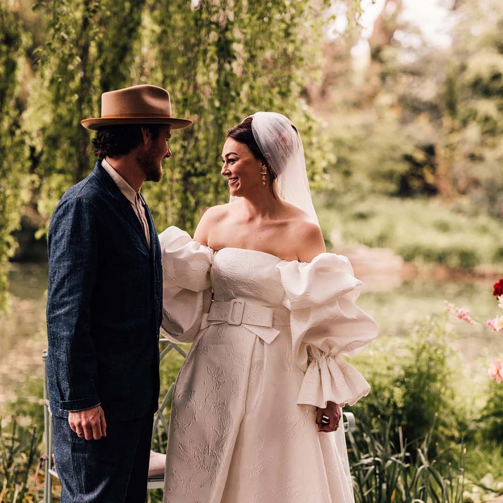 Bride in puff sleeve wedding dress by Jesus Peiro with the groom in a double denim suit with hat 