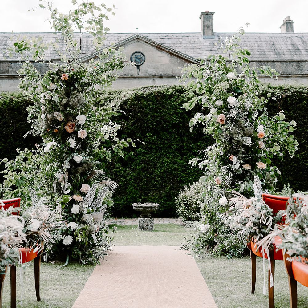 Flower columns decorating altar at Babington House outdoor wedding ceremony 