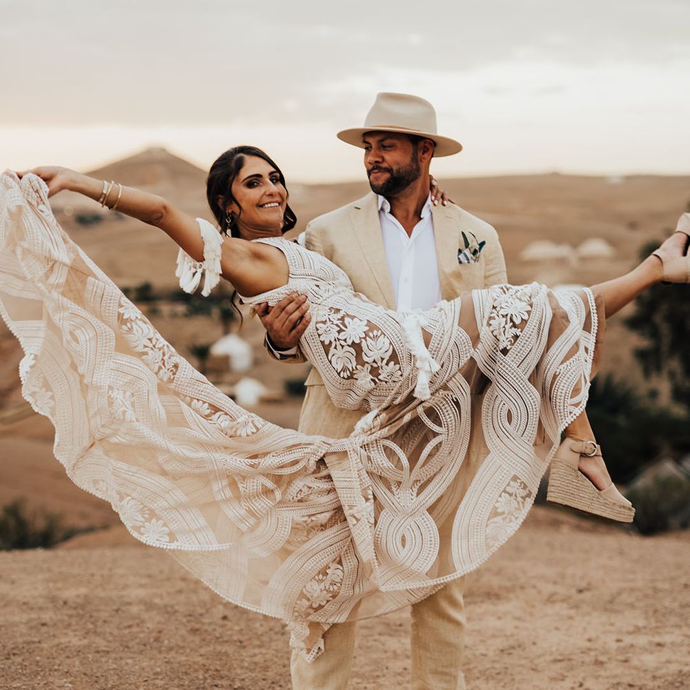 The groom spins the bride around in her boho lace wedding dress from Rue De Seine 