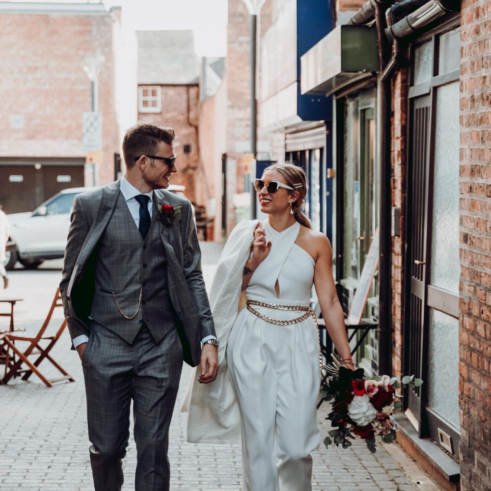 Stylish bride and groom walking down the street 