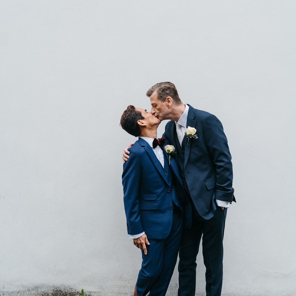 Grooms kiss on the morning of their wedding